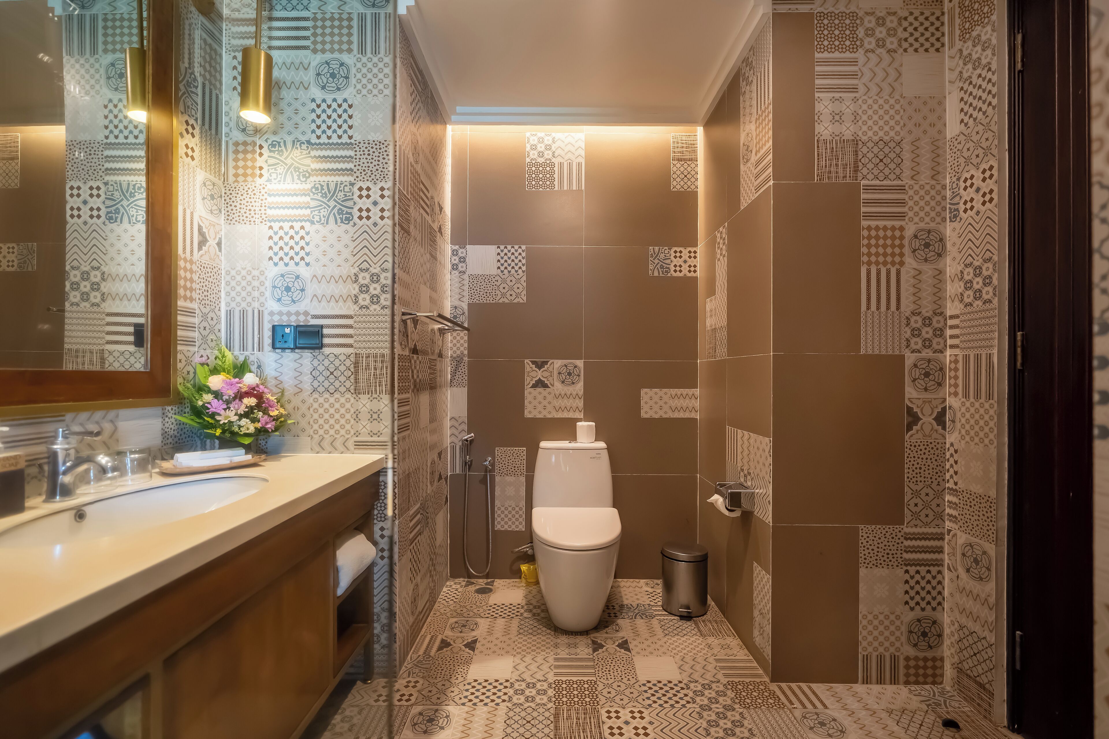 A modern bathroom with patterned tiles, a white sink, and a toilet.