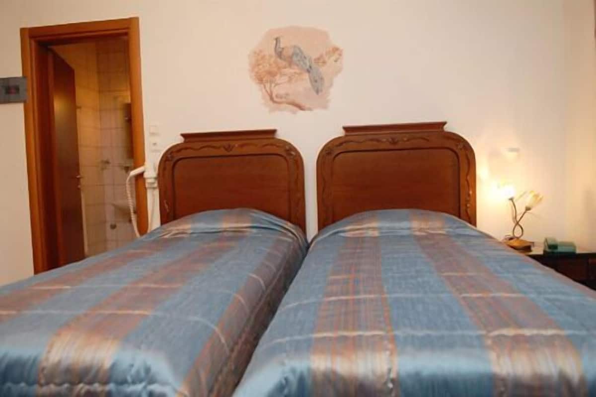 Un dormitorio con dos camas de madera, una obra de arte en la pared y una lámpara de noche.