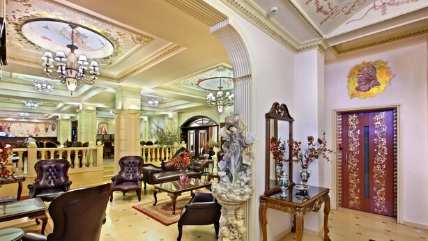 Un lobby imponente con candelabros ornamentados, muebles clásicos y una fuente decorativa.