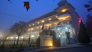 Un hotel con una entrada destacada, varios balcones y una fachada bien iluminada.