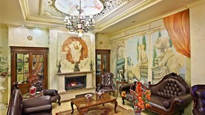 Una habitación elegante con chimenea, sillones de cuero, una mesa de centro de madera y un gran mural en la pared.