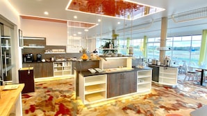 Una cocina moderna con una isla central, taburetes de bar y un ventanal con vistas al exterior.