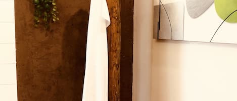 A room with a wooden towel rack, a green plant, and a modern abstract painting.