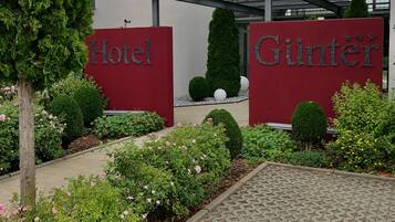 Ein Hotel mit modernem Design, dessen Eingang eine Glasfassade und ein rotes Schild mit dem Namen des Hotels zeigt.