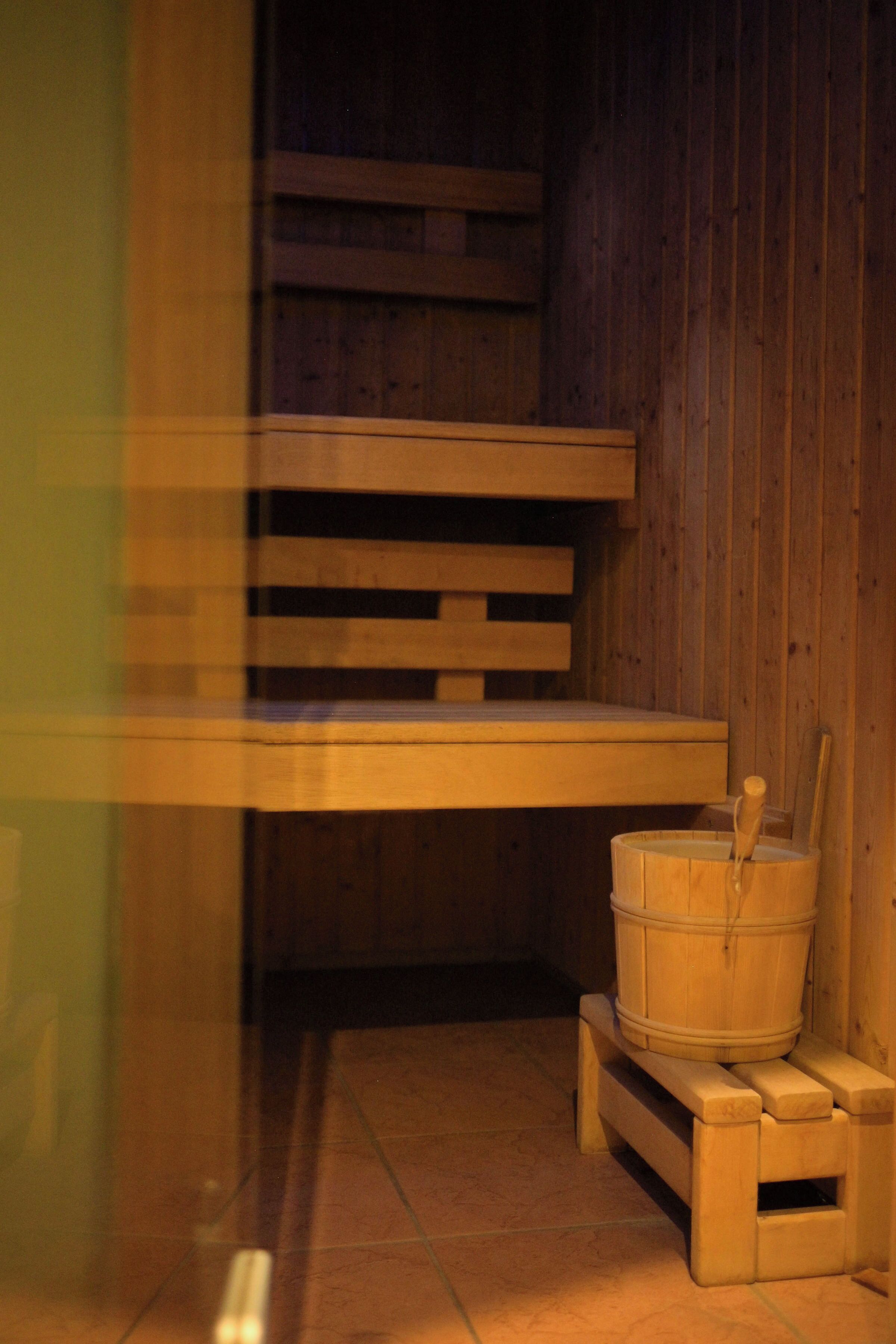 A sauna with wooden benches and a bucket.