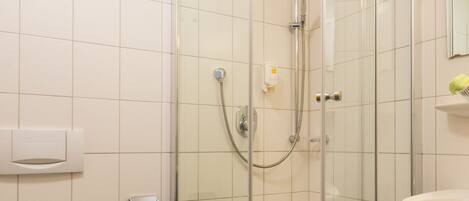 A modern bathroom with a glass-enclosed shower, a white toilet, and a sink with a mirror above it.