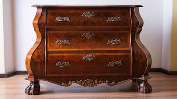 A wooden chest of drawers with ornate metal handles and a curved base.