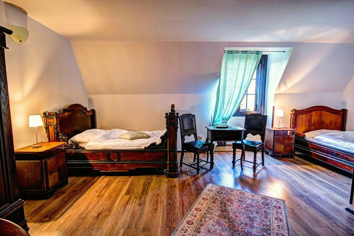 Een slaapkamer met houten vloer, een bed, een bureau, een stoel en een nachtkastje.