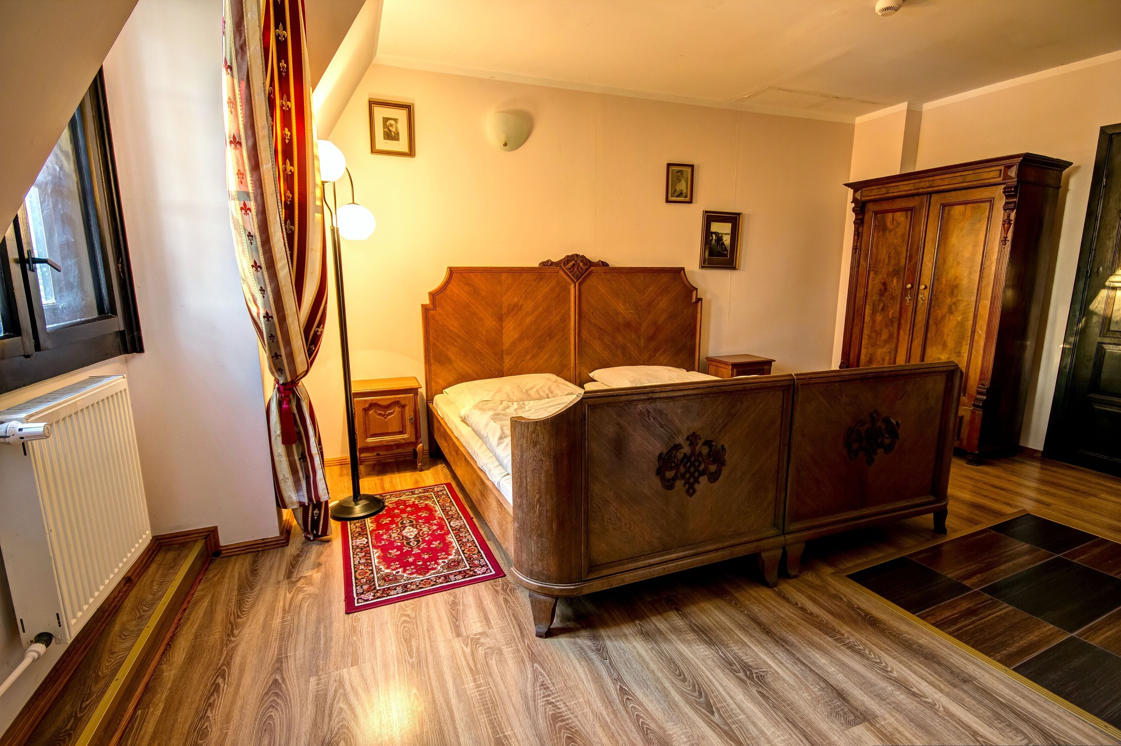 Ein Schlafzimmer mit einem hölzernen Bett, einem Heizkörper, einem Holzschrank und einem roten Teppich.