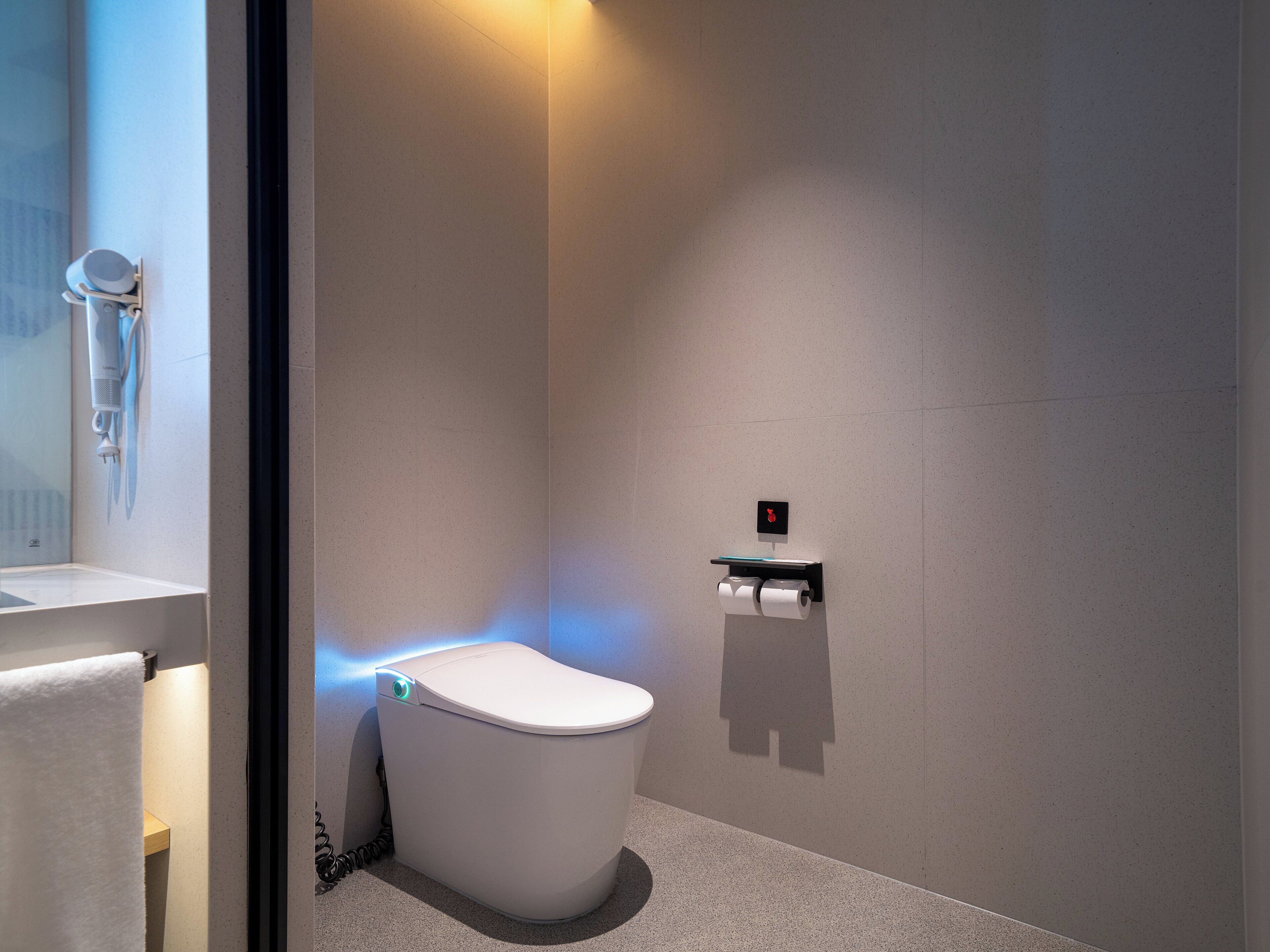 Un baño moderno con inodoro, barra para toallas y dispensador de papel.