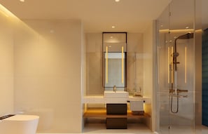 Casa de banho moderna com chuveiro de vidro, um espelho grande e lavatório branco.