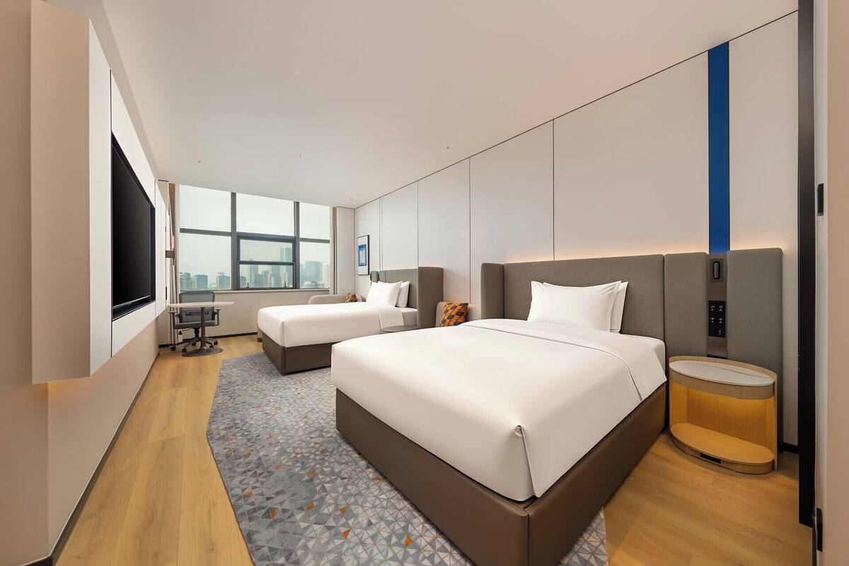 Ein modernes Hotelzimmer mit einem großen Bett, einem Schreibtisch und einem Fernseher.