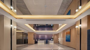 A modern hotel lobby with a reception desk, a high ceiling, and a mezzanine level. - Holiday Inn Express Yiwu International Trade City by IHG (Jinhua)