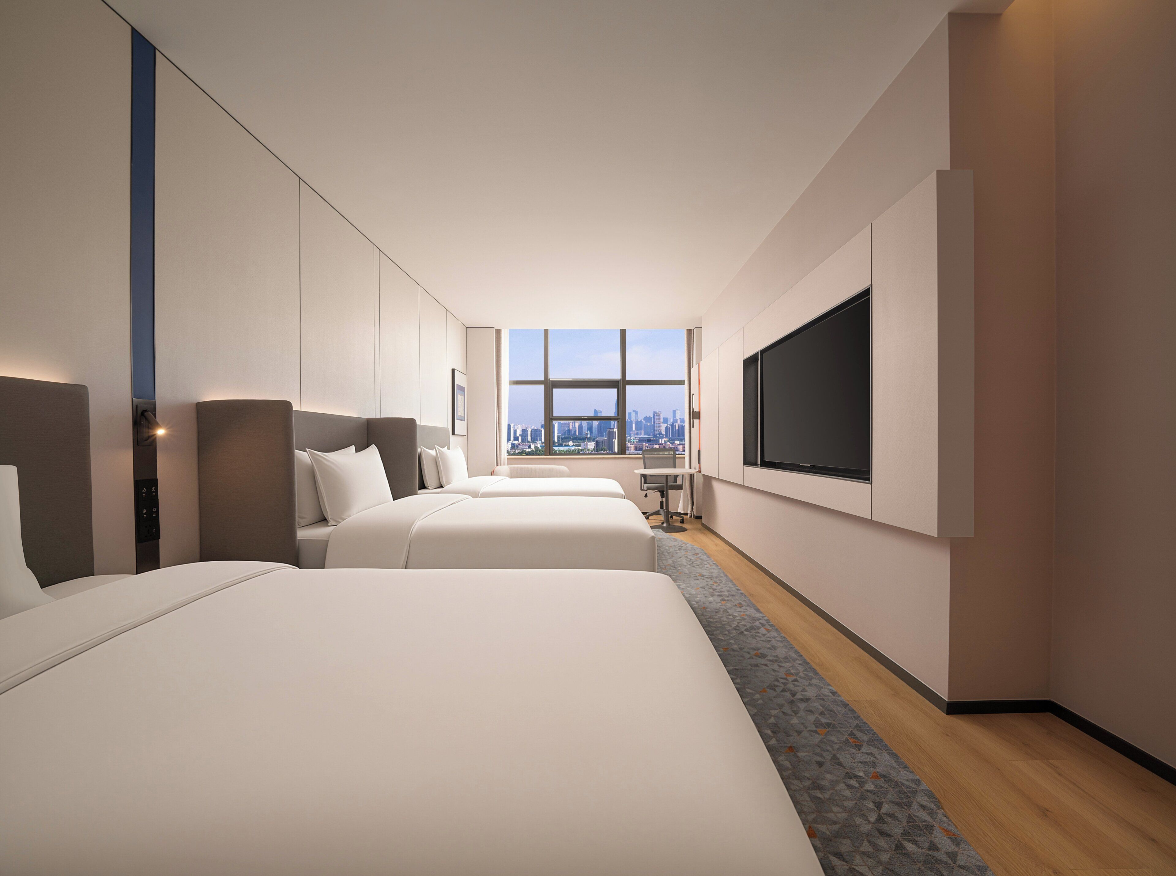 Habitación de hotel con dos camas, televisión, vista a la ciudad y escritorio.