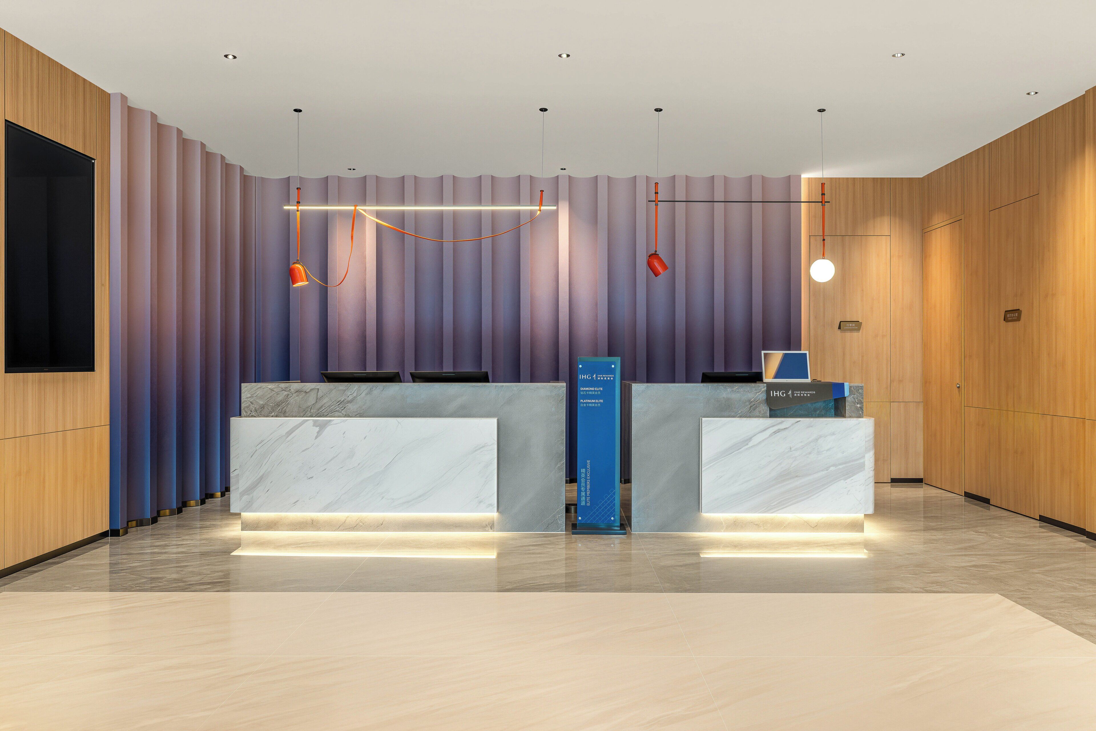 A reception desk with a marble top, a blue vertical sign, and a modern light fixture.