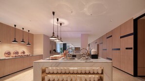 A modern kitchen with wooden cabinets, pendant lighting, and a marble island with cups. - Holiday Inn Express Yiwu International Trade City by IHG (Jinhua)