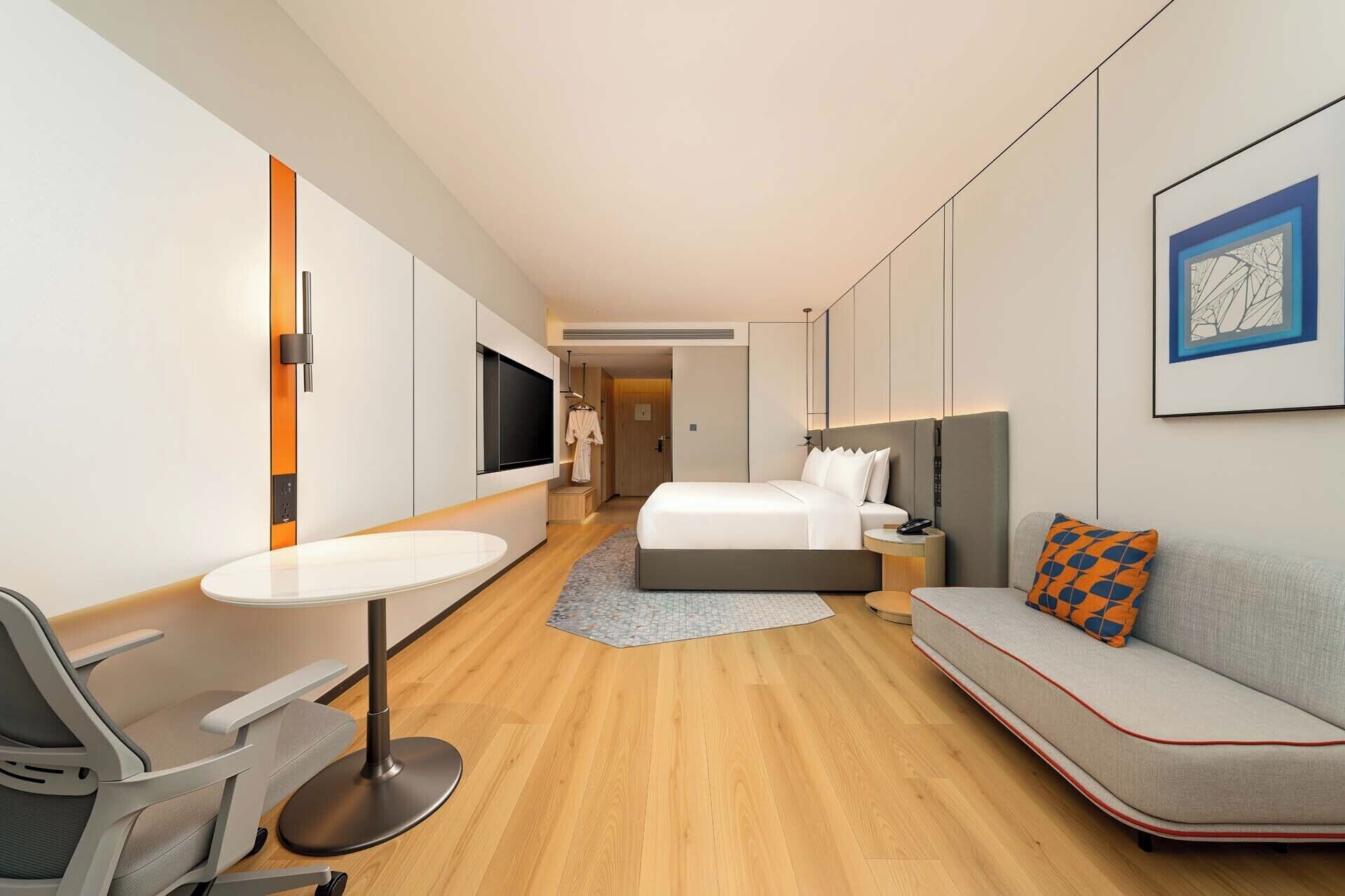Una habitación de hotel moderna con cama, sofá, escritorio y televisor.