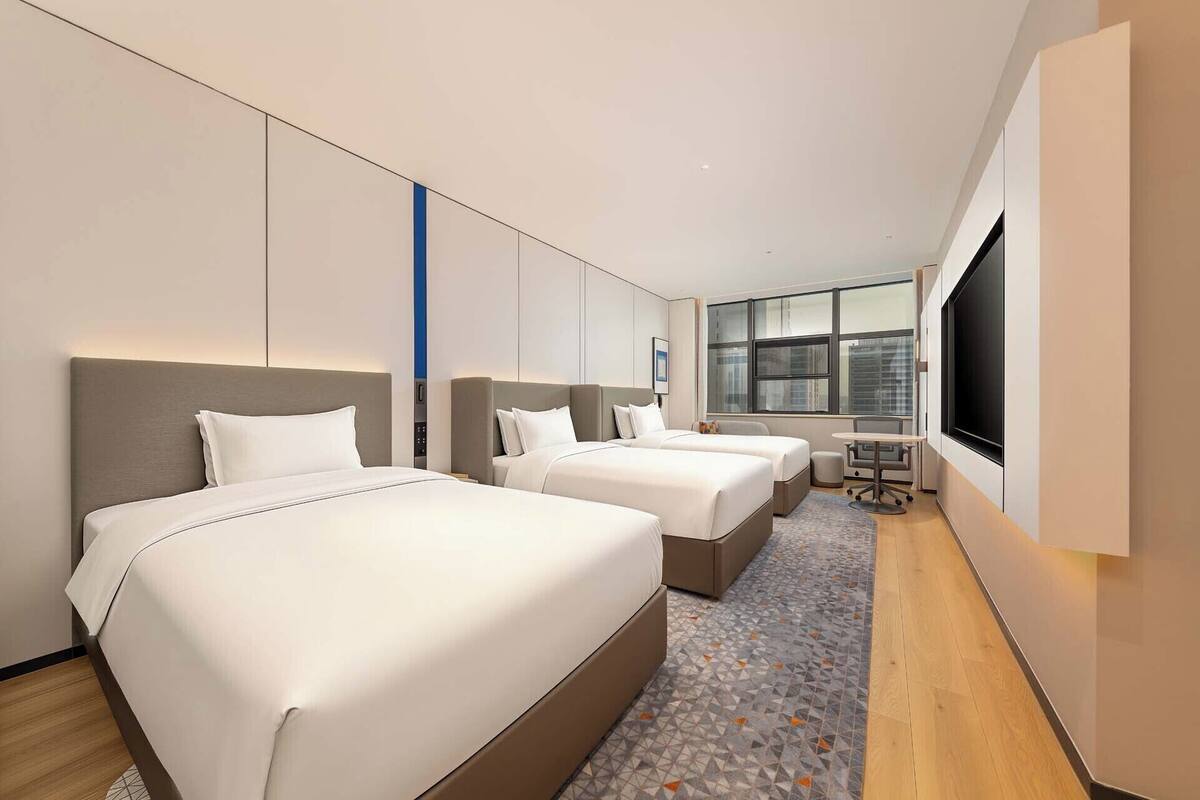 Ein Hotelzimmer mit zwei Betten, einem Schreibtisch und einem großen Fenster.