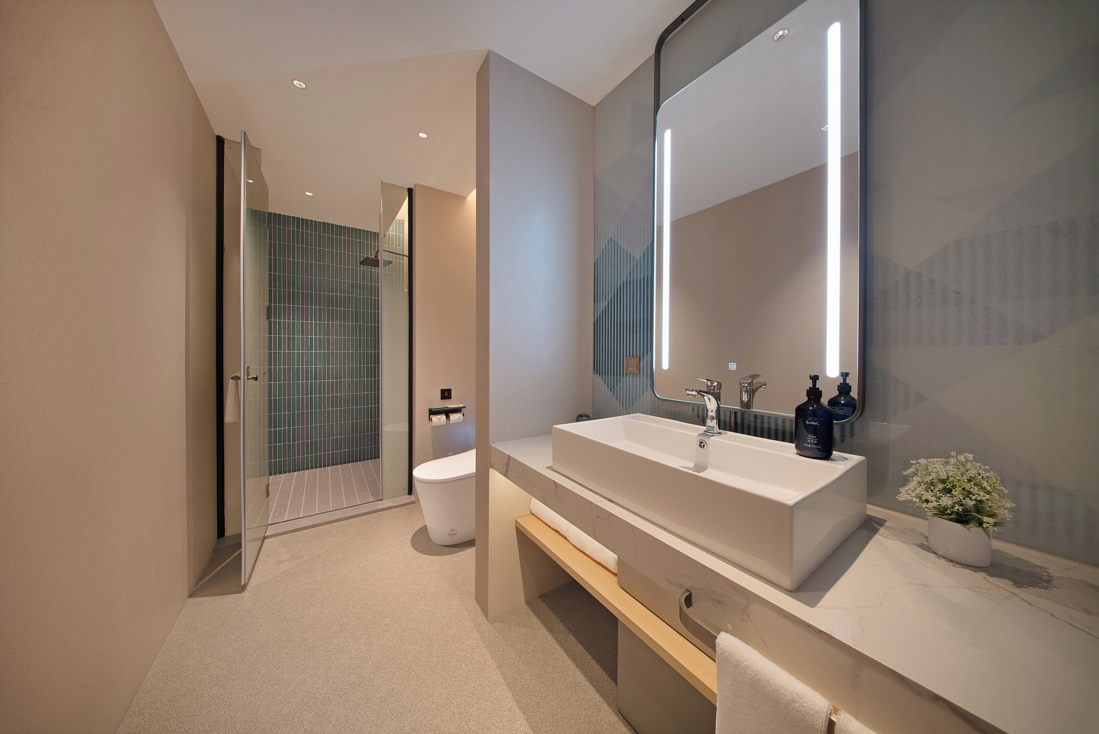 A modern bathroom with a large mirror, a white sink, and a shower area.