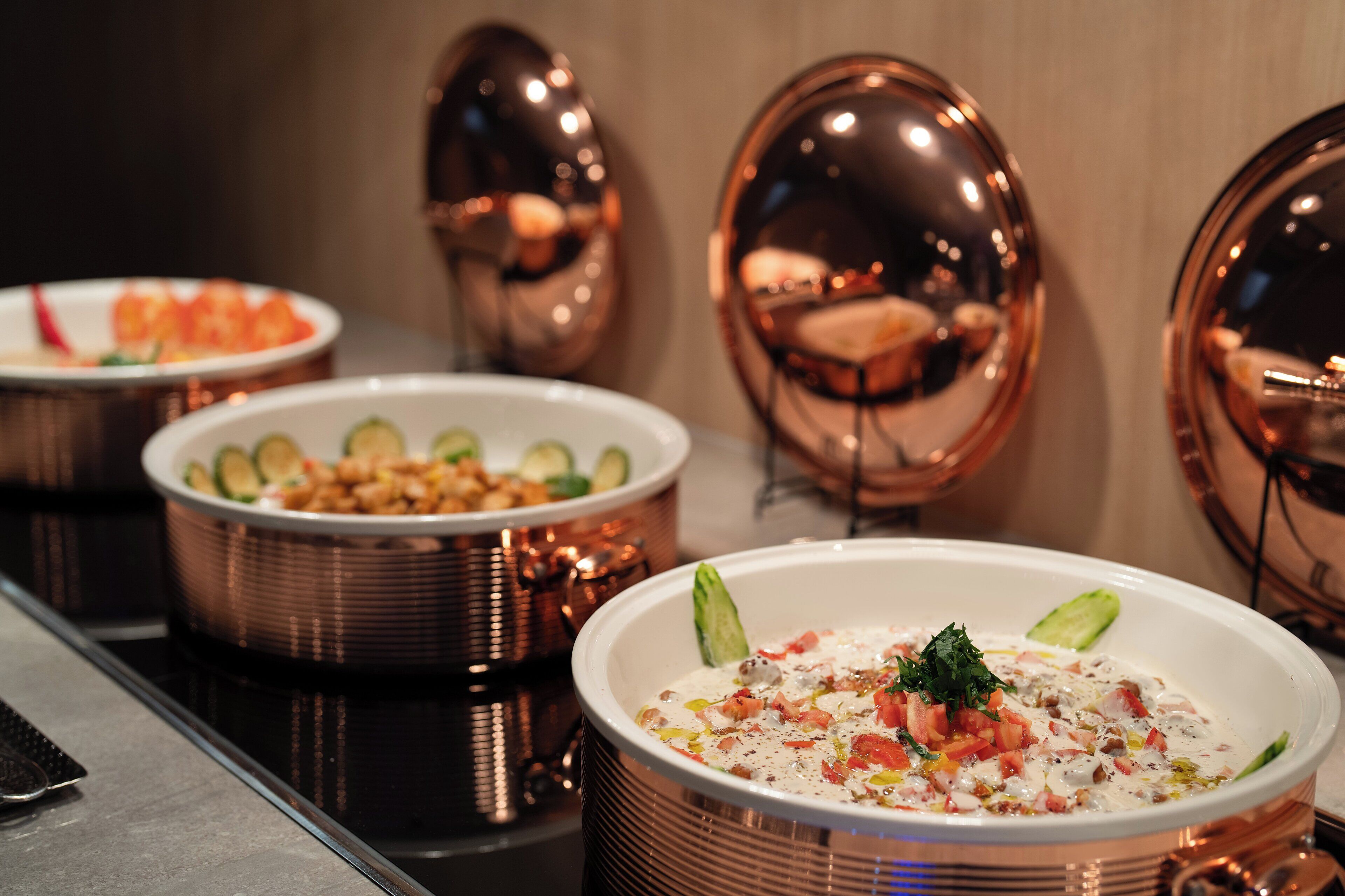 Un coin repas avec des bols en cuivre posés sur une table, une assiette contenant de la nourriture et un miroir décoratif.