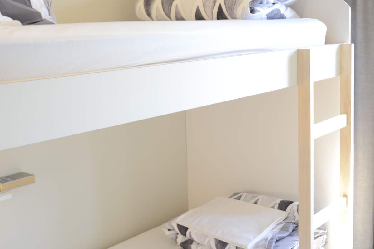 A bunk bed with a ladder, a pillow, and a blanket on the lower bunk.