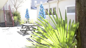 A patio area with a wooden table and chairs, a staircase, and a tree. - Bridge Backpackers (Nelson)