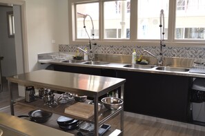 A modern kitchen with stainless steel appliances, a wooden island, and a window with a view of buildings outside.
