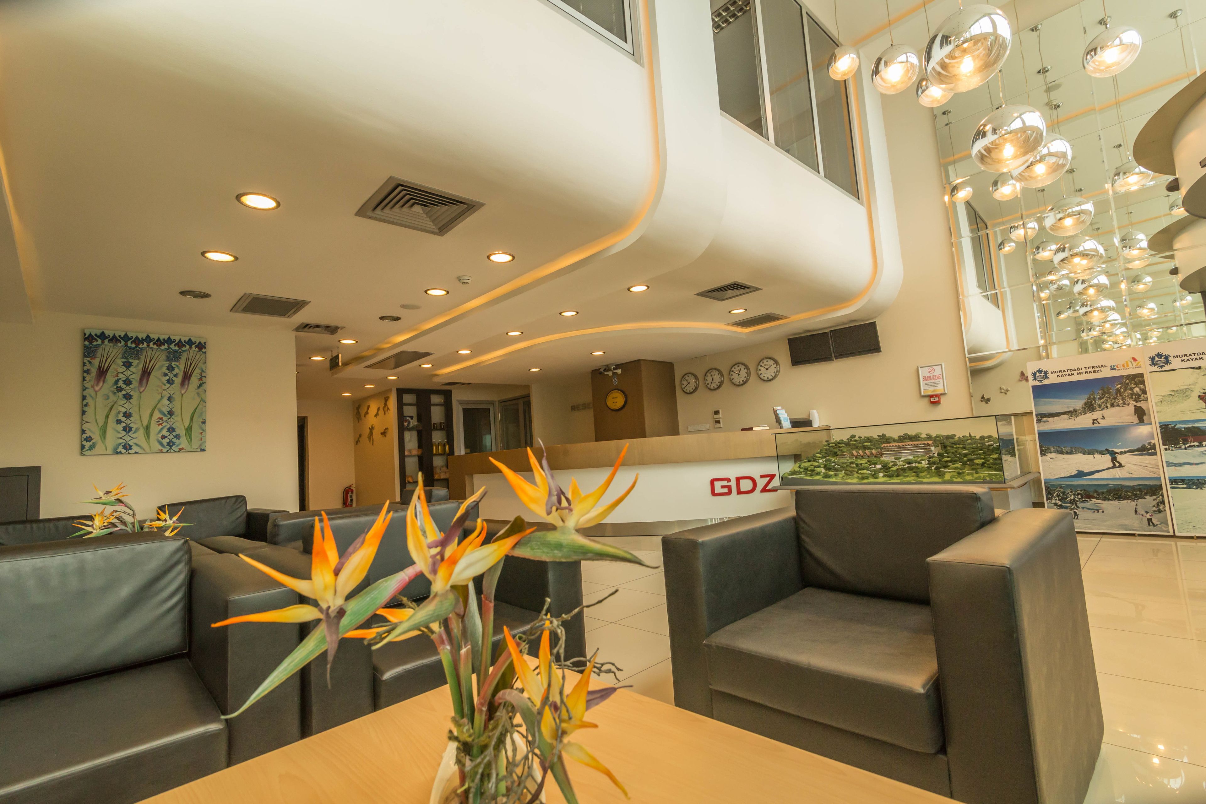 A modern hotel lobby with a reception desk, seating area, and decorative plants.