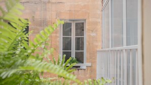 A window with a white frame and a small balcony with a white railing. - Valletta Rodrigo Apartment (Valletta)