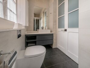 Ein modernes Badezimmer mit Toilette, Waschbecken und Spiegel.