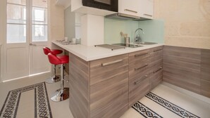 A modern kitchen with a built-in oven, a sink, and a bar stool. - Valletta Rodrigo Apartment (Valletta)
