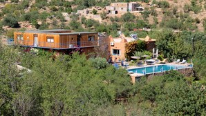 A villa with a pool, surrounded by trees and hills.