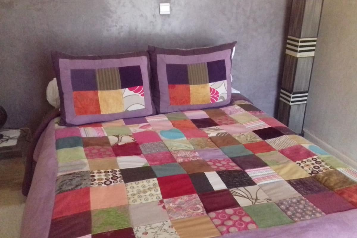 A bed with a colorful patchwork quilt and two pillows with a floral design.