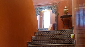 A staircase with patterned tiles leading to a room with a large mirror and a small table with a vase.