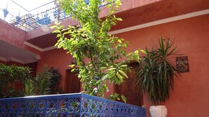 A courtyard with a blue wrought iron fence, potted plants, and a tiled floor.