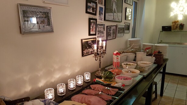 Tarjolla on runsas buffet, jossa on monenlaista ruokaa, sekä kynttilänjalka ja seinä, joka on koristeltu kehystetyillä valokuvilla.