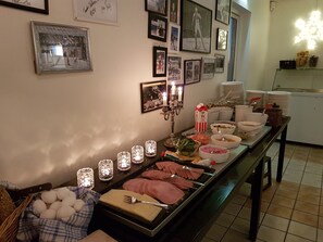 A buffet setup with various food items, a candle holder, and a wall decorated with framed photos. - Valbergsängen Hotell & Vandrarhem (Torsby)