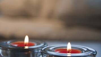 Dos velas encendidas en candelabros de vidrio sobre una superficie de madera.