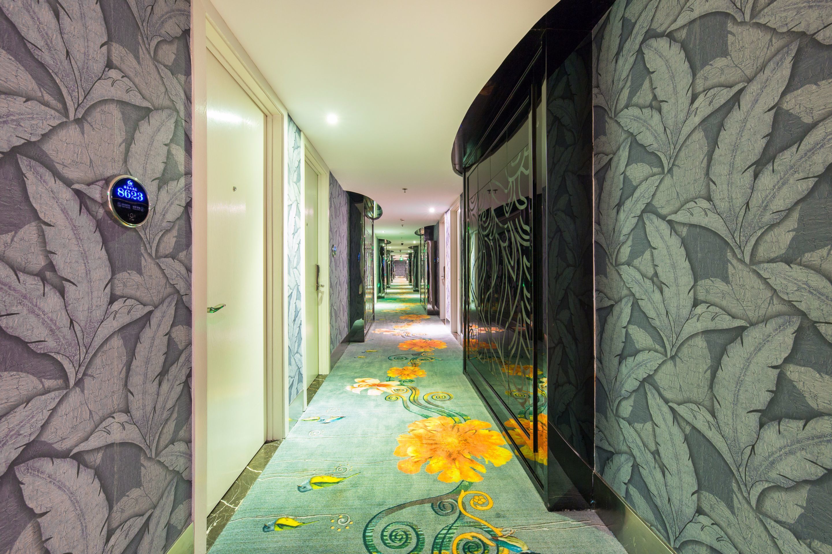 A hallway with a floral carpet design, a digital clock, and patterned walls.