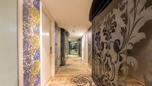 A hallway with patterned walls and a carpet with a large floral design. - Lvgu Hotel Yiwu (Jinhua)