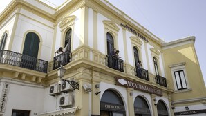 A building with balconies, air conditioning units, and storefronts labeled "Cremera," "Accademia del Gusto," and "Goloseria." - Suite Porta Terra (Gallipoli)
