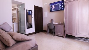 A room with a sofa, a desk, a television, and a wardrobe. - Suite Porta Terra (Gallipoli)