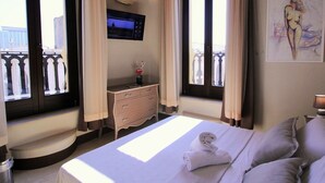A hotel room with a bed, a desk, a TV, and a painting on the wall. - Suite Porta Terra (Gallipoli)