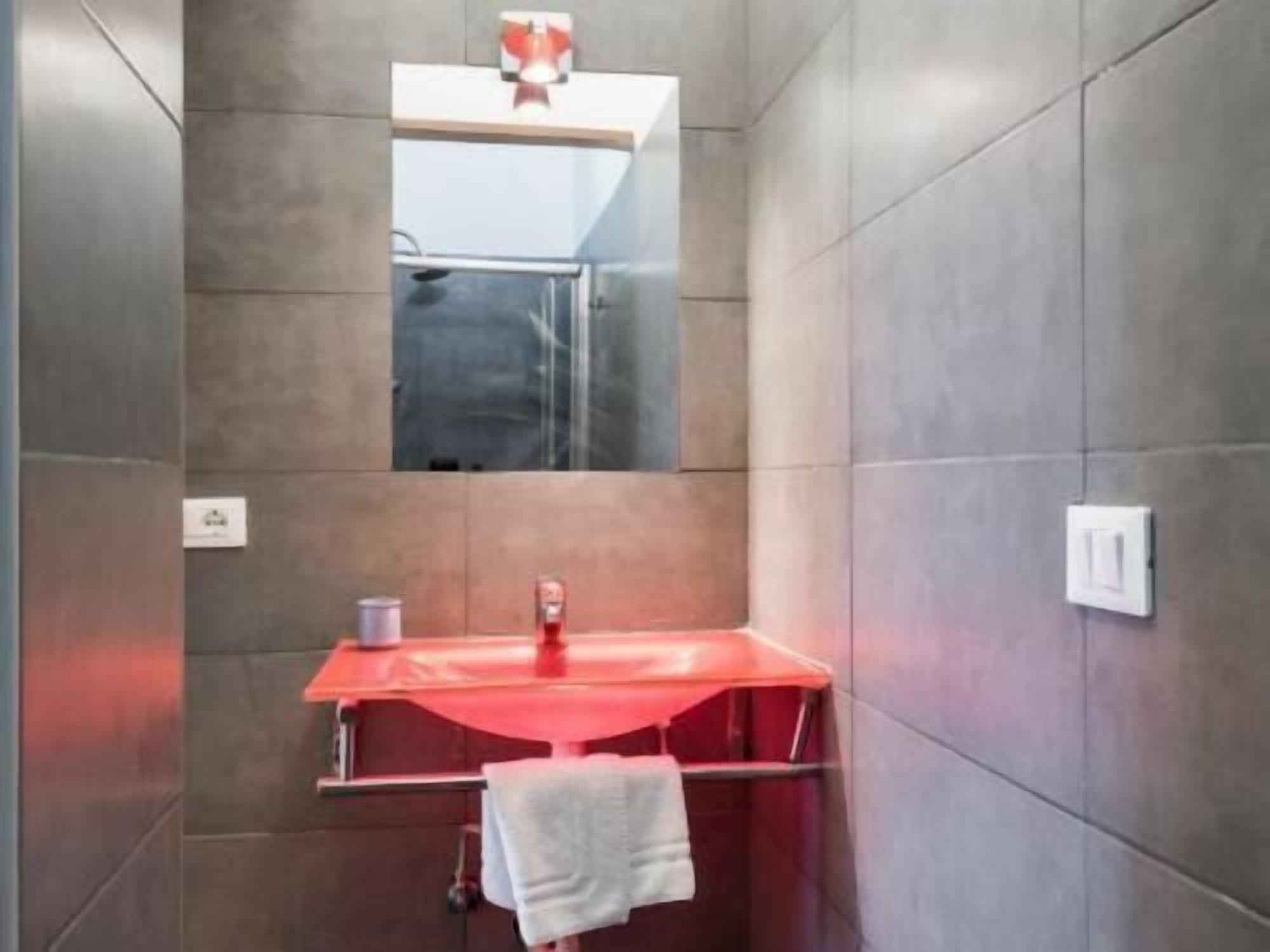 A bathroom with a red sink, a mirror above it, and a towel hanging on a rack.