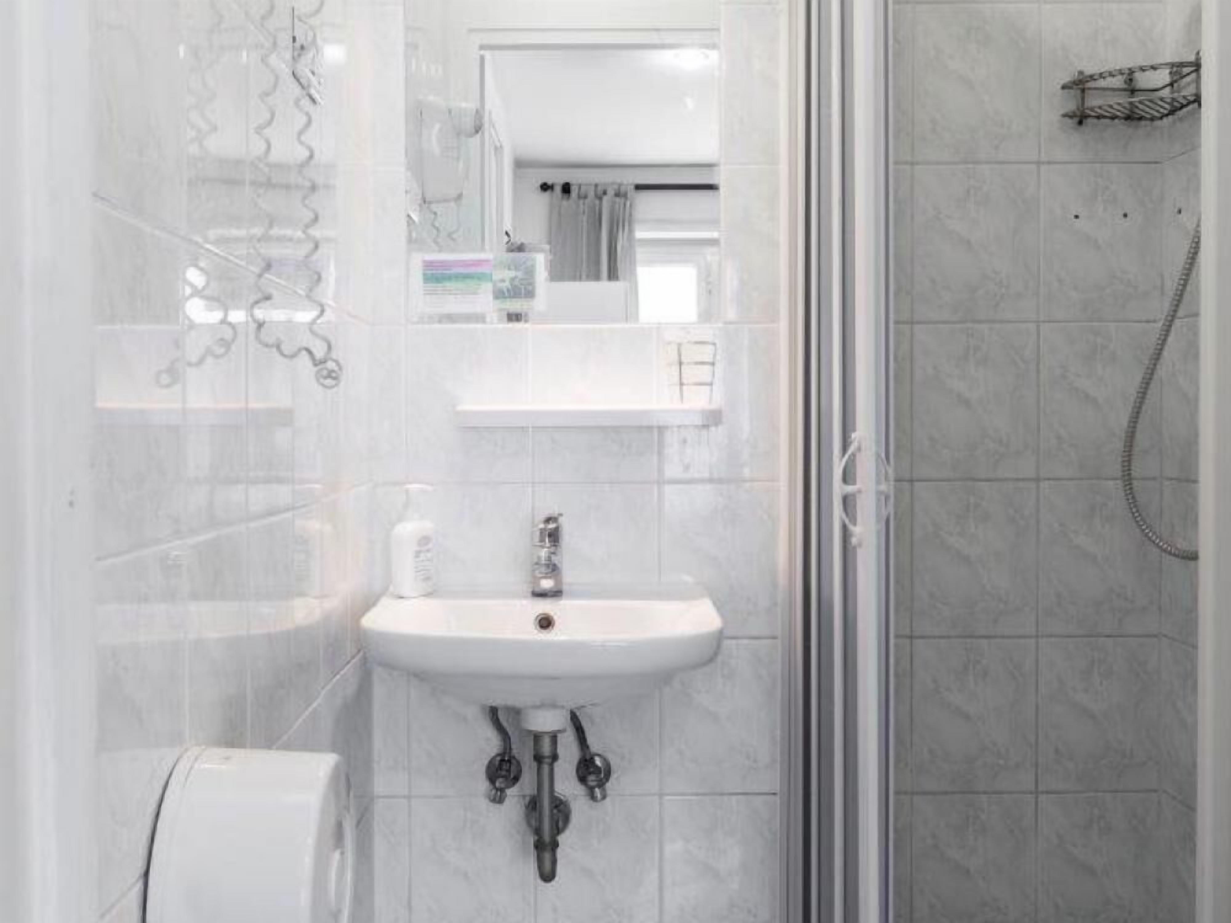 A bathroom with a white sink, a mirror, and a shower.