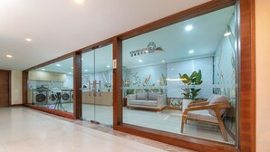 A modern laundromat with glass doors, a sofa, and a chair inside. - Yihohotel Xiang'An Xiamen (Xiamen)