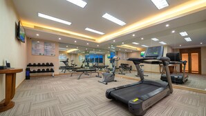 A gym with treadmills, elliptical machines, and free weights. - Yihohotel Xiang'An Xiamen (Xiamen)
