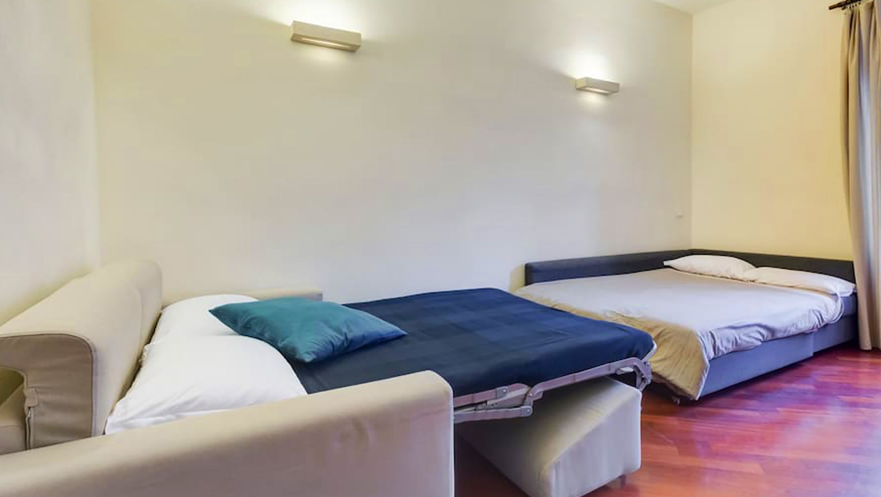 A room with two beds, a sofa, and a small table.