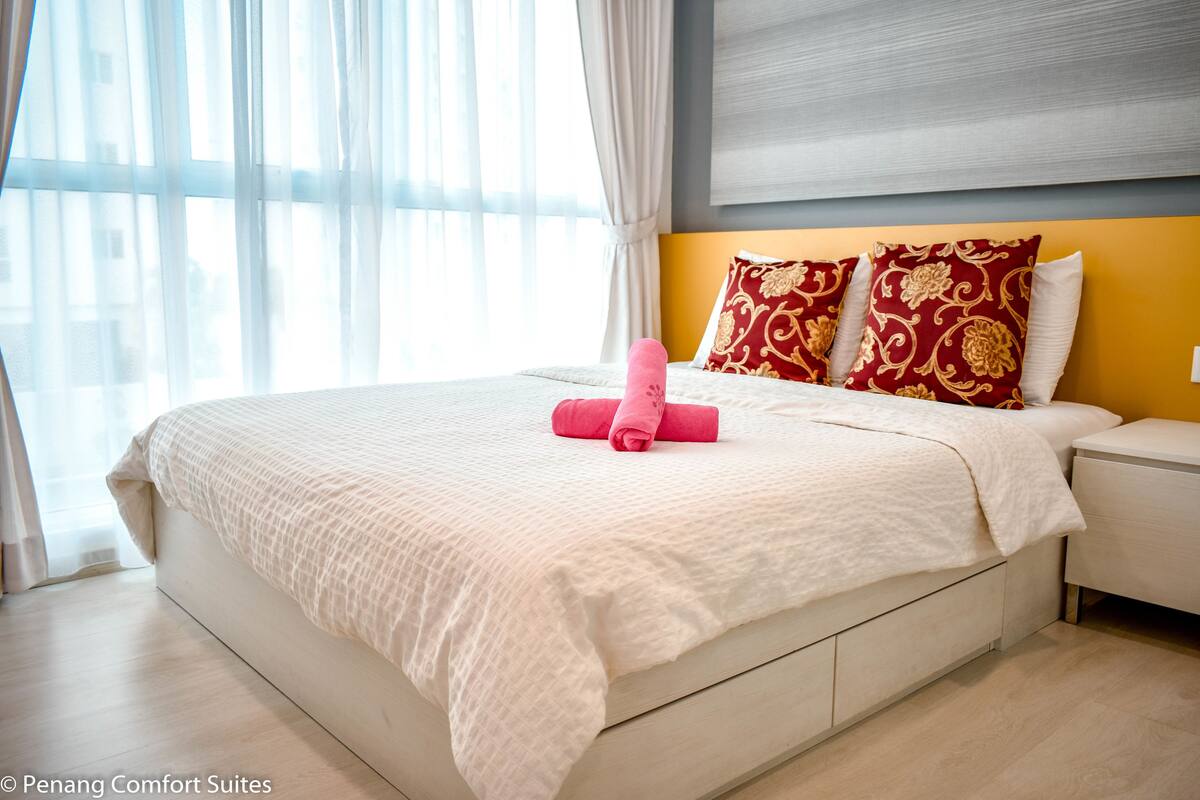 A hotel room with a large bed, white bedding, and decorative pillows.