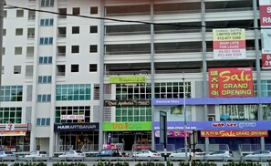 Un immeuble à plusieurs étages abritant divers commerces, notamment un salon de coiffure, une épicerie et un magasin d’électroménager.